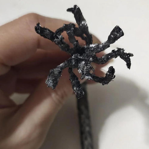 Graphite braided compression packing, black, 1/8 in x 1/8 in, for pump valves or mechanical seals, held in hand.