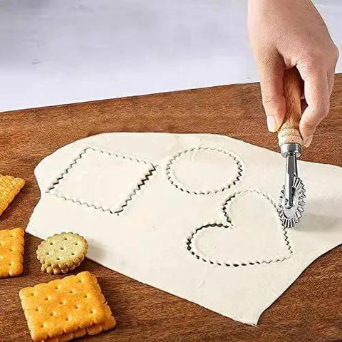Ultimate Pasta Wheel Cutter with wood handle and aluminum frame cutting pastry dough into shapes on wooden board.