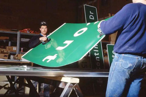 Workers using Beefy Flat Vacuum Cup 8 Inch Heavy Duty Lifting Tool for handling large road signs in a factory setting