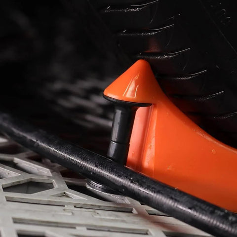 Close-up of Car Hose Guide Set Of 4 Automatic Plastic Hose Guides for a smooth roll under a tire on a textured surface.