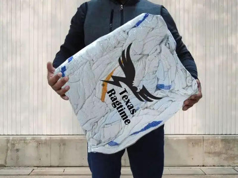 Person holding a large pack of Texas Ragtime rags wrapped in clear packaging, designed for cleaning purposes in various environments.