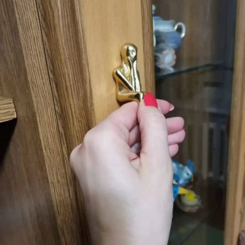 Close-up of a hand installing Brass Thinker Shape Cabinet Pulls Gold Finish Artful Abstract Drawer Handles for Cabinets and Furniture.