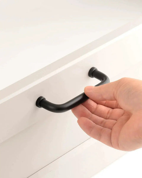 Hand holding Five Pack Matte Black Modern Cabinet Pulls 3.75 Inch Hole Center 96mm Dresser Drawer Handles on white cupboard
