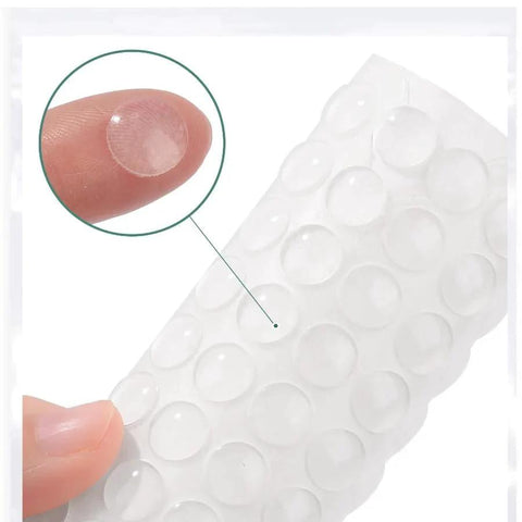 100 Pieces Clear Self Adhesive Cabinet Door Bumpers 0.4 Inch Diameter Rubber Dots Non Slip Soft Close Pads on fingertip close-up.