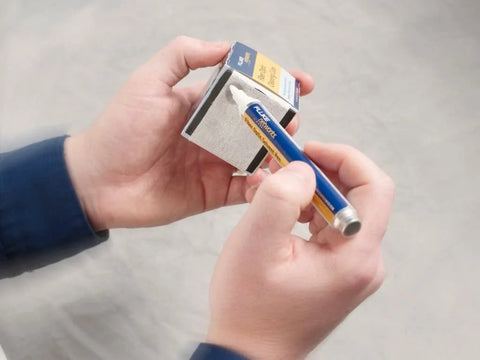 Fluke Networks NFC-SOLVENTPEN fiber optic cleaning solvent pen in blue, held by two hands