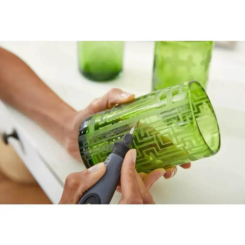 Person using Versatile 11 Piece Carving And Engraving Micro Accessory Kit For Dremel Rotary Tools to etch design on green glass