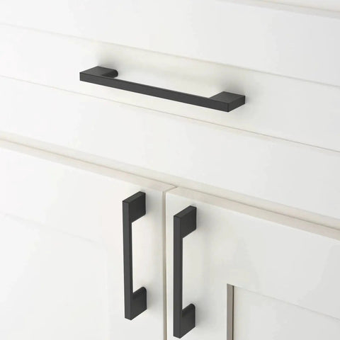 Matte black cabinet pulls installed on white cupboard drawers, featuring 10 Pack Matte Black Cabinet Pulls 5 Inch 128mm Hole Centers Kitchen Cabinet Handles For Cabinets Cupboard Drawers Hardware ZH0060 Durable, Easy To Install Long Lasting Finish.