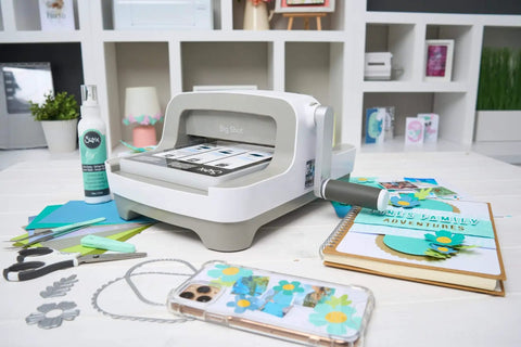 All In One 6 Inch Die Cutting And Embossing Machine Starter Kit for crafters on craft table with accessories and scrapbook
