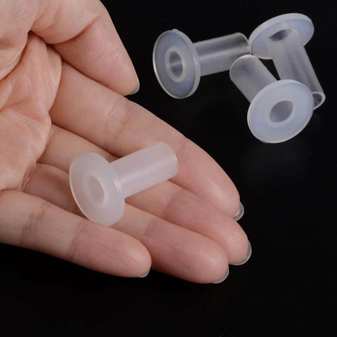 Two white self lubricating nylon flanged sleeve bearings white, 8mm bore, 10mm OD, 25mm length, 20mm flange diameter over black surface