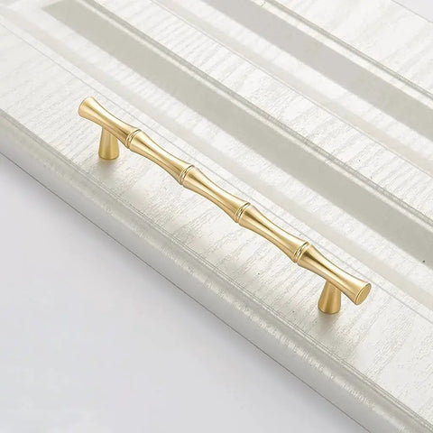 Bamboo Shape Solid Zinc Alloy Cabinet Knobs Set Of 6 In Golden Finish for drawers with smooth edges, shown installed on a panel.
