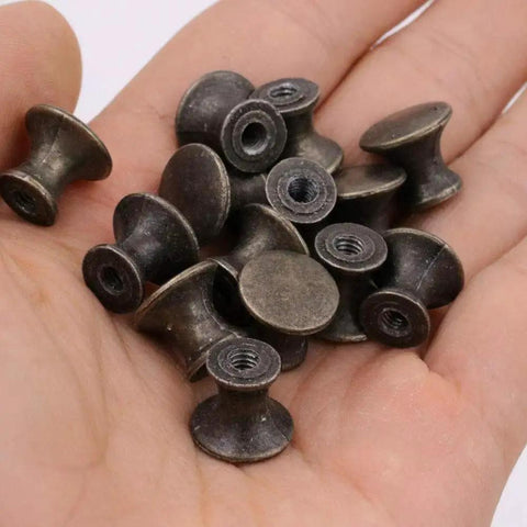 10 Pcs Vintage Bronze Drawer Pull Handles Zinc Alloy Mini Metal Knobs held in a hand, showing compact size and bronze finish.
