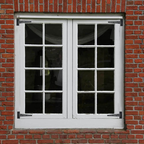 Black T-strap hinges on white-framed double windows in brick wall, part of 6 Pack 6 Inch T Strap Shed Hinges Heavy Duty Black For Barn Doors Sheds And Wooden Fences