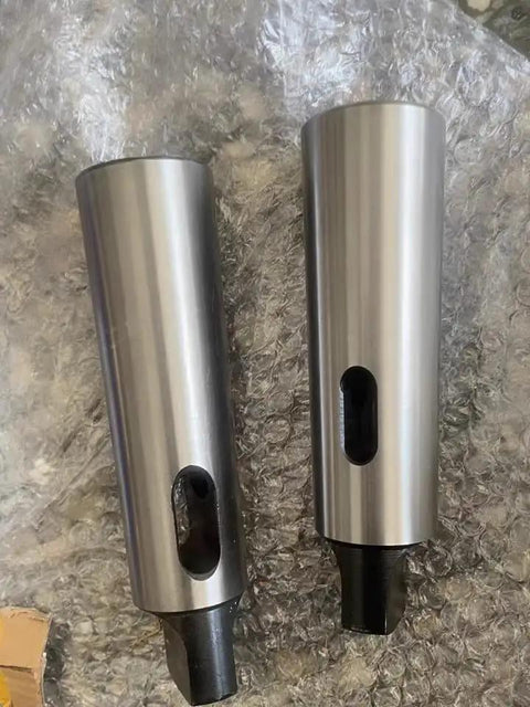 Two Morse taper reducing adapters; metal cylindrical sleeves with black taper ends and side oval slots.