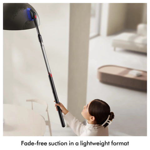 Dyson PencilVac Fluffycones cordless vacuum with long black wand and red controls, held by a child indoors.