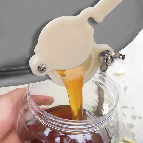 HunterBee honey gate valve for 5-gallon bucket, side view, white plastic with metal clamp.