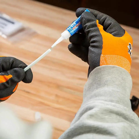 Applying glue from Non Conductive Fish Tape Repair Kit For Fiberglass Tapes Made In USA with gloves on wood table.