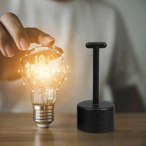 Nonslip Socket Ring Removal Tool For E14 E26 E27 G9 Lamps No Sweat Install tool next to glowing light bulb on wooden surface