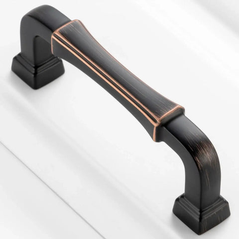 Close-up of a 10 Pack 3 Inch Oil Rubbed Bronze Cabinet Pull with Bronze Brushed Finish on a white cabinet, featuring smooth edges.
