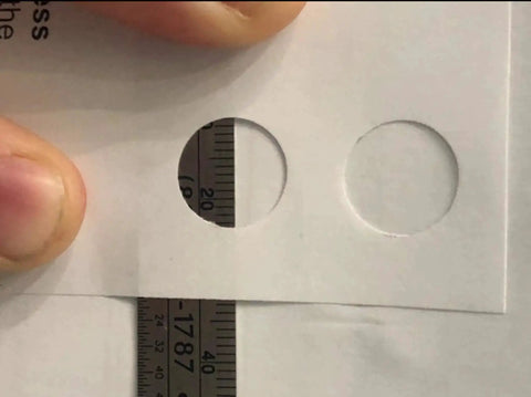 Close-up of 13mm round holes punched in paper using Hand Held Slot And Thirteen Millimeter Round Hole Punch Tool 2-In-1 Diy Puncher.