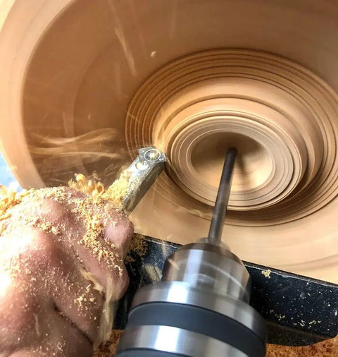 Close-up of 90 Detailer Carbide Wood Lathe Turning Tool for Fine Detail Work, cutting into wood on a lathe, creating smooth curves.