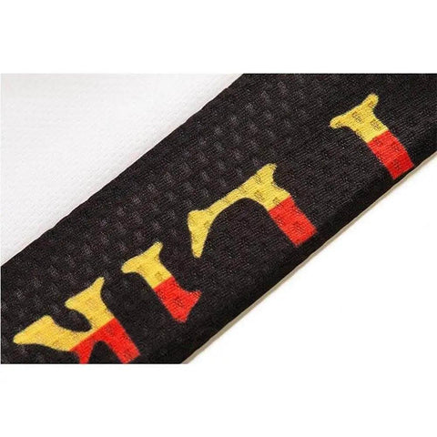 Close-up of black textured fabric with yellow and red letter pattern, highlighting detail.