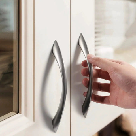 Hand installing a 10 Pack Brushed Nickel Cabinet Pulls 5 Inch Arch Twisted Silver Handles for drawers in a modern kitchen