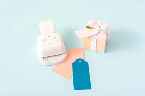 3-In-1 Round Tag Punch For Crafting And Scrapbooking, multi-color tool with gift tags and small wrapped gift box on pastel background
