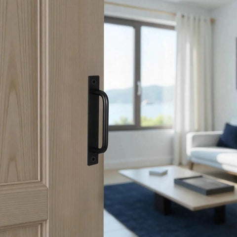 Close-up of black barn door handle on wooden door with modern living room background, highlighting 12 Pack Black Barn Door Handle Cabinet Pulls Aluminum Alloy 5.8 Inch Long With Screws For Kitchen Cabinets Cupboards Wardrobes Closets Sheds Garages And Sliding Barn Doors Perfect For Upgrading Drawer Pulls And Cabinet Hardware.