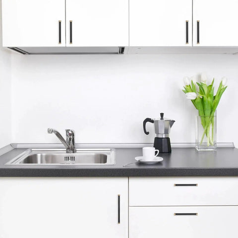 Modern kitchen with black and champagne bronze knurled cabinet handles installed on white cabinets and drawers