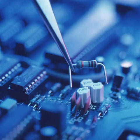 Axial resistor with color bands, close-up view held by tweezers over a blue circuit board