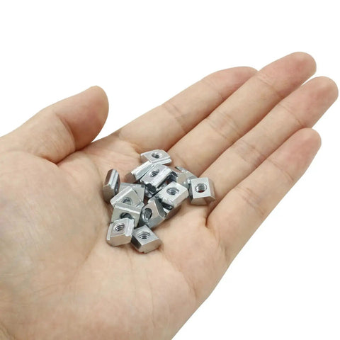 Hand holding 50Pcs 2020 Series Sliding T Nuts Carbon Steel M4 T Slot Nut Hammer Head M3 T sliding nuts for aluminum profiles, nickel plated