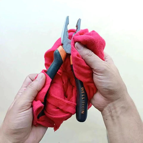 Hands holding a colorful recycled cotton rag with pliers, from a 50 lb box of extra absorbent T-shirt scraps for shop use.