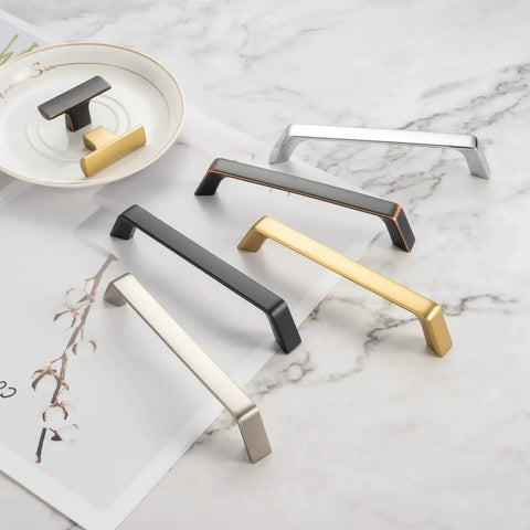 Various styles of cabinet pulls in different finishes on marble surface, including 10 Pack 5 Inch Oil Rubbed Bronze Cabinet Pulls Set For Kitchen Cabinets Drawers.