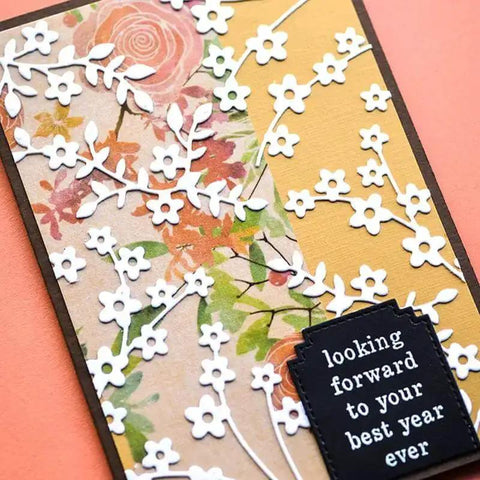 Handmade card with floral paper, die cut white flowers, and black tag reading 'looking forward to your best year ever'