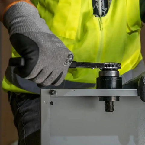 Worker using Knockout Punch Set With Wrench For Electrical Conduit One Half Inch To Two Inch Sizes Includes Punches Dies Draw Studs
