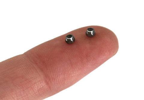 Close-up of two Stainless Steel Fingerboard Lock Nuts With Nylon Inserts Pack Of Six on a fingertip, pro-grade hardware.