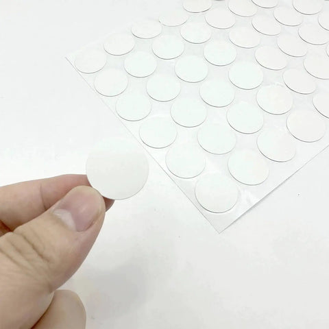 Close-up of a hand holding a round PVC sticker from the White Screw Hole Cover Set including 290 pieces in three sizes.