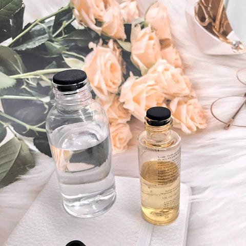 Glass bottles with liquid on a table with roses, featuring black caps, related to 80 Pieces Silicone Hole Plugs Kit With 7 Sizes.