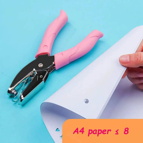 Mini One Quarter Inch Circle Hole Punch With Pink Soft Grip shown punching a 1/4 inch hole in paper, suitable for crafting and scrapbooking.