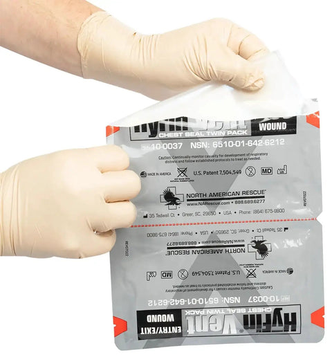 Hands holding Twin Pack HyFin Vent Chest Seal for trauma and wound care with three channel pressure relief vents package.