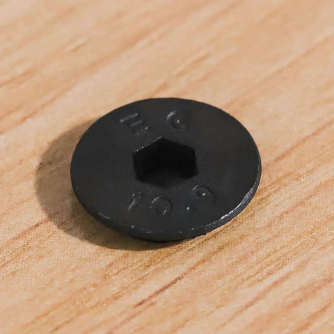 Close-up of top view M5 flat head socket cap screw, black oxide finish, 10.9 grade alloy steel, focus on hex socket and engravings.