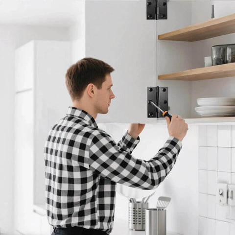 Man installing 3 Inch Black Door Hinges 12 Pack on kitchen cabinet door, showcasing 304 stainless steel construction with screwdriver.