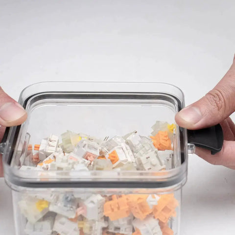 Hands closing a Durable Sealed Switch Storage Box For Mechanical Keyboard Switches Transparent 460ml Clear Plastic Case