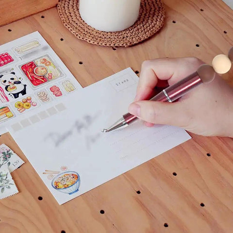 Person writing with beadable pen, next to stickers on wooden table.