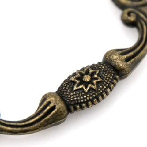 Close-up of vintage antique brass bail pull handle detail for wooden drawers, featuring retro diamond base and press forged detail.