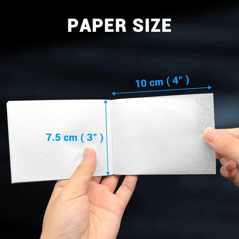 Hands holding open booklet of 700 Sheets Lens Cleaning Tissue Paper for Microscopes and Camera Lenses with size dimensions shown.