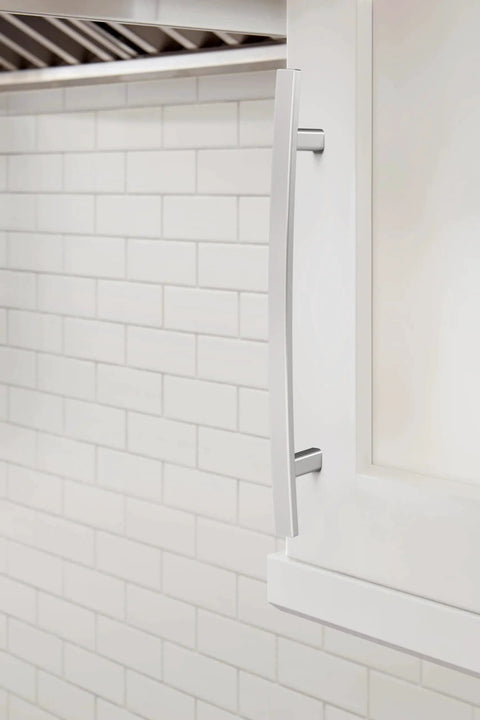 Side view of Cyprus Six And Five Sixteenths Inch Center To Center Polished Chrome Cabinet Pull installed on white cabinet