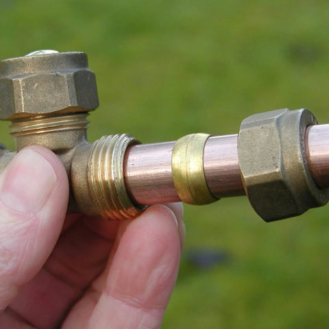 Brass compression fittings on copper tube with two nuts and ferrule, 1/4 in. tube OD, close-up view