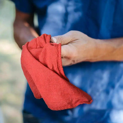 Person holding Heavy Duty Shop Towels 50 Pack Cotton Rags 14 By 14 Inches Lint Free Commercial Grade Red For Wet Or Dry Cleaning