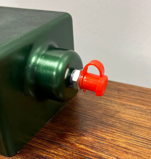 LockNLube grease fitting caps, red plastic cap on a grease zerk with hex nut mounted on a green metal surface.